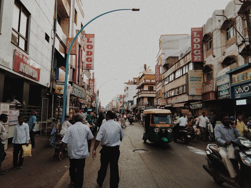 Lively street in Belgaum, India with people, shops, and vehicles in an urban setting.
